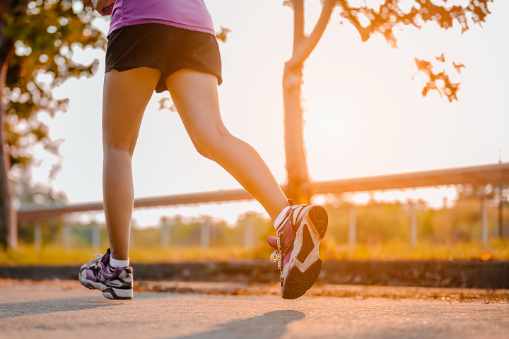 A woman running in the orange glow of a sunrise